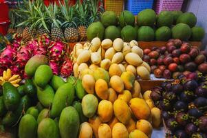 assortment of tropical fruits on market in Asia. Exotic fruits on counter in a street store in Vietnam. Mango, pitahaya, pineapple, mangosteen and passion fruit photo