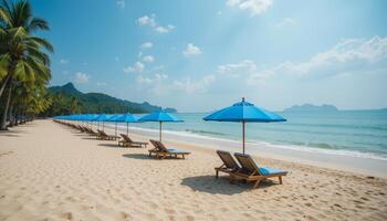 Rows of empty beach chairs with blue umbrellas on a pristine, white sandy beach, inviting calmness and tranquility for vacationers and beach lovers. photo