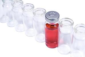 Phial with red vaccine in the row of empty vials photo