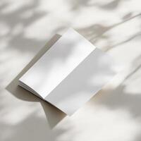 Blank white notebook on a table with shadow photo