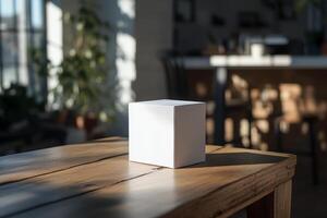 A white cube sitting on a table in front of a window photo