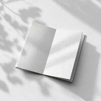 Blank white book on a white surface with shadow photo