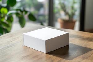 White cube mockup on wooden table with plant in background photo