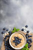 vertical image top view bowl of oatmeal with blueberries on linen napkin on grey concrete background with copy space, healthy and tasty breakfast concept photo