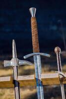 ancient arms displayed vertically in a wooden stand in a reenactment medieval event medieval combat weapons photo