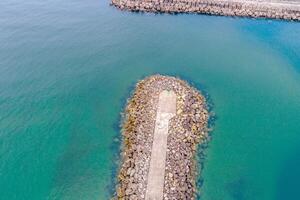 drone aerial view of a breakwater in the ocean, coastal infrastructure aerial view of a rocky jetty photo