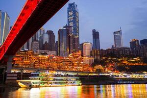 Chongqing, China - APR 02, 2025- Twilight Cityscape of the famous downtown shopping complex Hongyadong with illuminated bridge and highrise building in Chongqing, photo