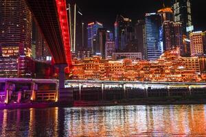 Chongqing, China -APR 02, 2025- Night view Cityscape of the famous downtown shopping complex Hongyadong with illuminated bridge and highrise building in Chongqing, China photo