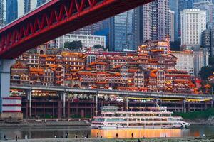 Chongqing, China-APR 02, 2025-Twilight Cityscape of the famous downtown shopping complex Hongyadong with illuminated bridge and highrise building in Chongqing photo
