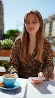Young businesswoman relaxing at outdoor cafe, drinking coffee while scrolling smartphone during sunny day, embodying modern urban lifestyle and digital connectivity video