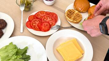 Caucasian male assembling fresh burger with lettuce, tomatoes, cheese for summer BBQ or Fourth of July celebration photo
