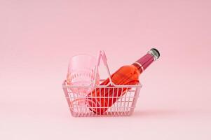 Watermelon drink and pink drinking glass in pink shopping basket on pastel pink background. Minimal refreshing summer drink concept. Trendy summertime party idea. photo