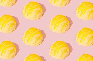 Yellow banana ice cream pattern on pastel pink background. Summer food concept. Minimal isometric layout. Ice cream scoop aesthetic background idea. photo