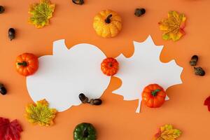 Creative autumn pattern of colorful autumn leaves, pumpkins and nuts with leaf and pumpkin shape paper card note copy space on orange background. Minimal season concept. Fall aesthetic. Flat lay. photo