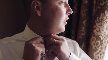 Stylish man in jacket fastens buttons, buttoning white shirt preparing to go out near window video