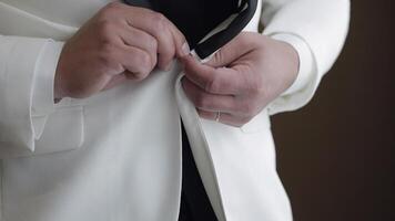 Groom buttoning jacket, man in suit fastens buttons on his jacket preparing to go out video