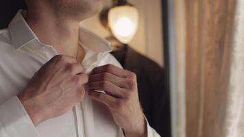 Stylish man in jacket fastens buttons, buttoning white shirt preparing to go out near window video