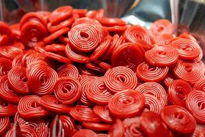 Bright red candy spirals in close-up view, showcasing texture and color at a dessert table during a celebration event photo
