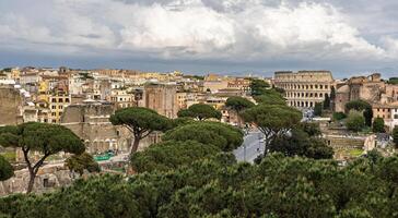 Historic landscape featuring ancient ruins and the Colosseum in Rome with overcast skies during midday photo