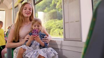 Child girl with mother using mobile phone internet social network application while traveling by bus video