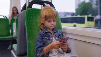 Little girl on smartphone, chatting, texting, browsing social media while traveling by bus in city video