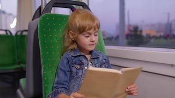 Portrait of attractive little child girl kid sitting at empty subway train, reading interesting book video