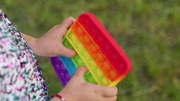 Child girl playing colorful squishy silicone bubbles sensory toy simple dimple pop it game, close-up video