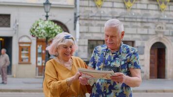 Senior grandmother and grandfather tourists looking for a place to go in new city using paper map video
