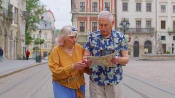 Senior grandmother and grandfather tourists looking for a place to go in new city using paper map video
