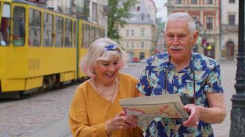 Senior stylish tourists man and woman having a walk and look for way using paper map in old city video