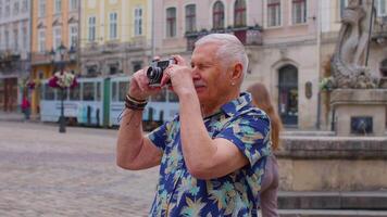 mayor hombre turista tomando imágenes con foto cámara en verano ciudad centro, vida después Jubilación video
