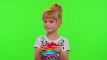Stylish child girl playing colorful squishy silicone bubbles sensory pop it toy game on chroma key video