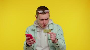 Man use mobile cell phone and plastic credit bank card, browsing say wow yes found out great big win video
