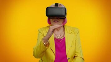 Senior woman using virtual reality VR app headset helmet to play simulation 3D game, drawing video