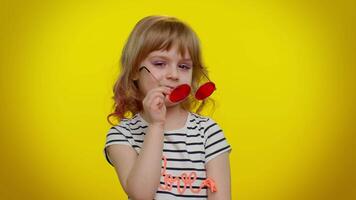 Happy playful kid girl in sunglasses blinking eye, looking at camera with smile, winking, flirting video