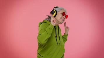 Senior woman listening music on headphones dancing disco fooling, having fun, gesticulating hands video