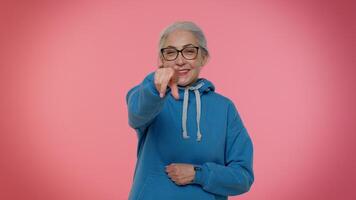 Elderly amused woman pointing finger to camera laughing out loud of ridiculous appearance funny joke video