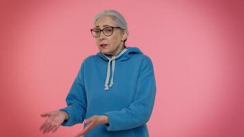 Senior woman raising hands in indignant expression, asking why, what reason of failure, irritation video