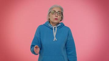 Elderly granny old woman closing eyes with hand showing stop gesture, confused shy scared to watch video