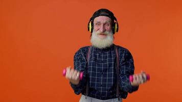 Elderly bearded man listening music via headphones, working out, lifting pink dumbbells, healthcare video
