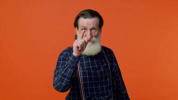 Senior old man pointing to camera with playful happy expression, making choice, showing direction video