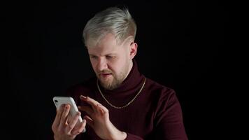Smiling shocked happy winning of man with blue eyes while browsing on smartphone on black background video