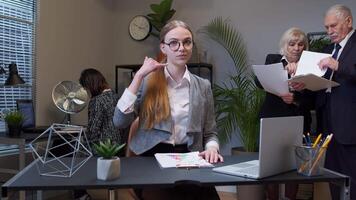 Portrait of business woman in office looking camera doing phone gesture like says hey you call me video