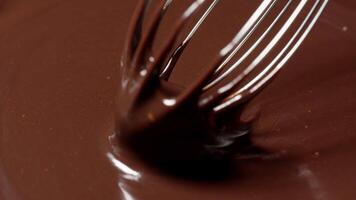 Slow motion mixing, stirring premium dark melted chocolate with a whisk, process of making sweets video