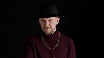 Facial expression of handsome man in stylish hat looking at camera and smiling on black background video