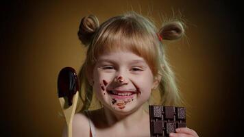 Joyful smiling child kid girl with dirty face from melted chocolate on dark background in studio video