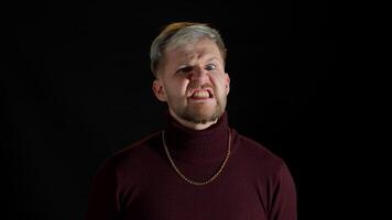 Disappointed handsome man with blue eyes showing negative and agressive emotion on black background video