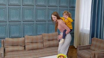 Happy family mother and child kid daughter dancing, playing piggyback, running, riding at home video