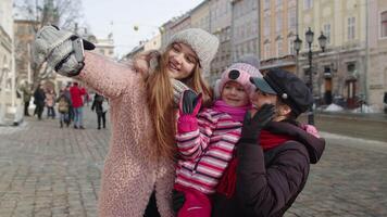 mujer turistas tomando selfie fotos en móvil teléfono con adopción niño niña en invierno ciudad calle video