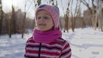 Smiling child kid girl tourist walking, having fun on snowy road in winter sunny park forest, sunset video